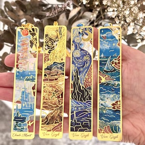Könnte beinhalten: Vier goldfarbene Metall-Lesezeichen mit berühmter Kunst. Das erste Lesezeichen ist ein Gemälde von Claude Monet, die nächsten drei sind Gemälde von Van Gogh. Jedes Lesezeichen hat ein einzigartiges Design mit farbenfrohen Details.