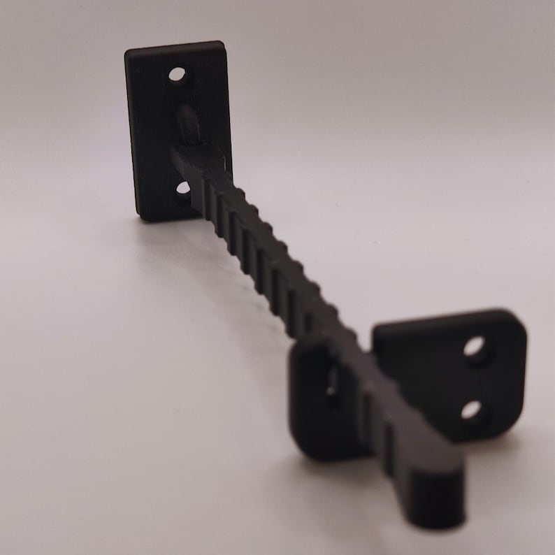 K&ouml;nnte beinhalten: Eine schwarze Metallhalterung mit einer rechteckigen Montageplatte und einem strukturierten, abgewinkelten Arm. Die Halterung hat zwei L&ouml;cher in der Montageplatte und zwei L&ouml;cher in der anderen Platte.