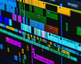 Könnte beinhalten: Nahaufnahme eines Computerbildschirms, der eine Videobearbeitungszeitlinie mit farbigen Blöcken zeigt, die verschiedene Videoclips und Audiospuren darstellen.
