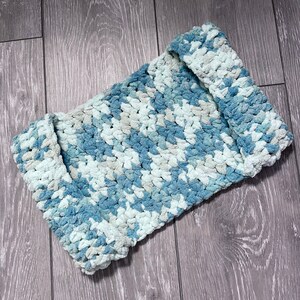 May include: A blue and white crocheted blanket with a textured, fluffy look.