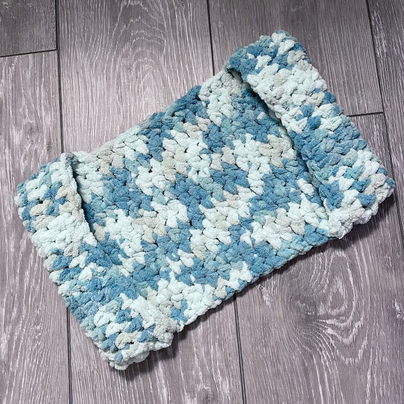 May include: A blue and white crocheted blanket with a textured, fluffy look.
