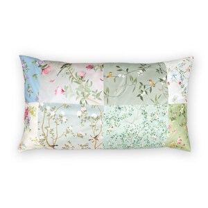 Könnte beinhalten: Rechteckiges Kissen mit einem Patchwork-Design mit Blumen- und Vogelmotiven. Die Abschnitte des Kissens zeigen verschiedene Pastellfarben, darunter Hellblau, Grün und Rosa, mit detaillierten Illustrationen von Blumen, Blättern und Vögeln.