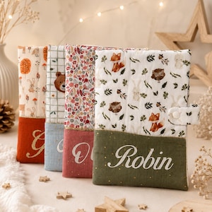 Peut inclure: Quatre protège-carnets rectangulaires en tissu, chacun doté d'une partie supérieure à motifs et d'une partie inférieure unie avec un prénom brodé en écriture blanche. Les couvertures sont équipées d'une fermeture à bouton-pression latérale.