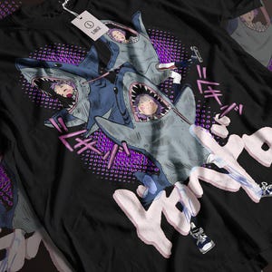 May include: Black t-shirt with a graphic print of three cartoon characters riding on sharks. The characters are wearing colorful clothing and the text "Kimetsu no Yaiba" is printed in pink on the shirt.