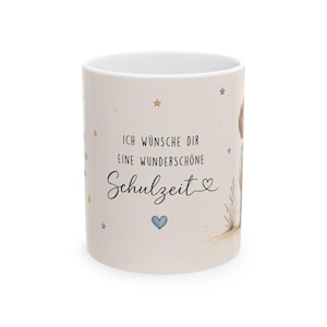 Könnte beinhalten: Eine weiße Keramiktasse mit beigem Hintergrund, verziert mit blauen und goldenen Sternen. Die Tasse zeigt den Text "ICH WÜNSCHE DIR EINE WUNDERSCHÖNE Schulzeit" in schwarzer Schrift sowie ein blaues Herz. Auf der rechten Seite befindet sich eine Aquarellillustration einer Person.
