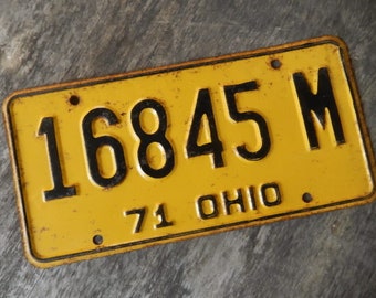 May include: A yellow metal license plate with black lettering. The plate reads "16845 M" and "71 OHIO".