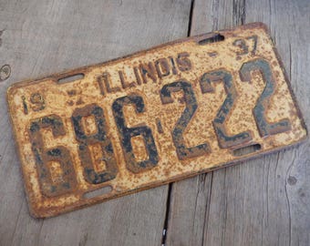 May include: A vintage Illinois license plate with the number 686222. The plate is rusty and faded, with black lettering on a yellow background.