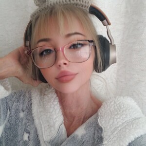 K&ouml;nnte beinhalten: Eine Frau tr&auml;gt einen grauen und wei&szlig;en Bademantel mit Sternenmuster, eine Brille und ein geh&auml;keltes Stirnband mit B&auml;renohren. Sie tr&auml;gt Kopfh&ouml;rer &uuml;ber den Ohren.