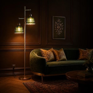 May include: A floor lamp with a tall, slender metallic pole and two adjustable arms. Each arm holds a bell-shaped, textured green glass shade that emits a warm, soft glow. The lamp features a circular base and a simple, functional design.
