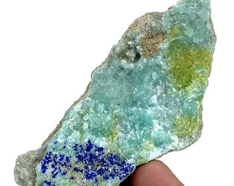 May include: A mineral specimen featuring a mix of colors and textures. The stone has a light blue-green base with clusters of small, crystal-like formations. Patches of yellow-green and deep blue are also visible, creating a striking contrast. The stone has a rough, natural appearance.