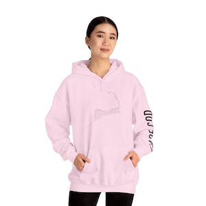 May include: A light pink hooded sweatshirt featuring a black outline of Cape Cod on the front. The right sleeve has the words "CAPE COD" printed vertically in black. The sweatshirt has a front pocket and a drawstring hood.