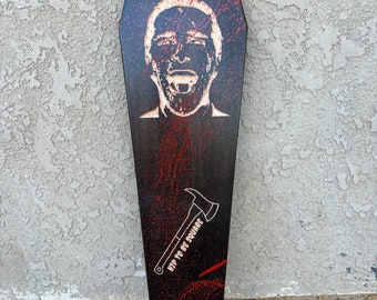 May include: A black and red longboard skateboard with a white stencil of a man's face and an axe with the text "Up to be square".