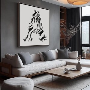 May include: A black and white abstract art print of the letter A, framed and hanging on a gray wall in a modern living room with a white sofa and a wooden coffee table.