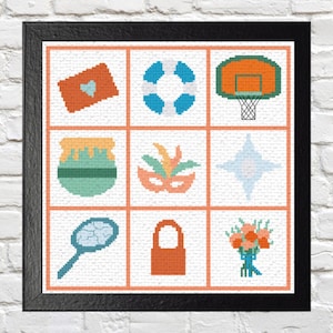 Op de afbeelding: Een ingelijst kruissteekkunstwerk met negen pixelachtige iconen. De iconen zijn een brief met een hart, een reddingsboei, een basketbalring, een honingpot, een masker, een ster, een tennisracket, een hangslot en een boeket bloemen. De lijst is zwart.