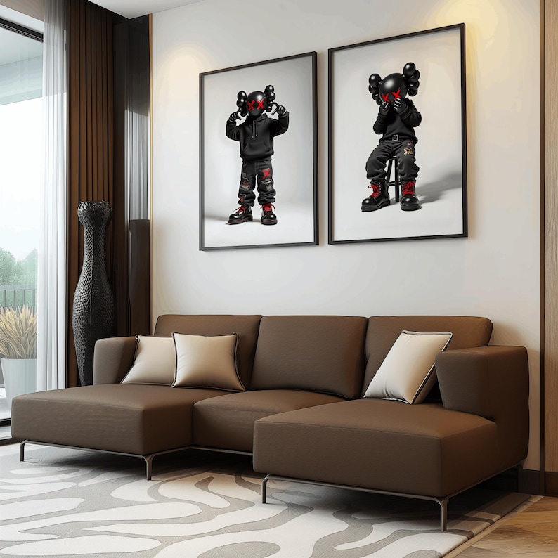 May include: A brown sectional sofa with two pillows, positioned in front of a white wall with two black framed prints of cartoon figures.