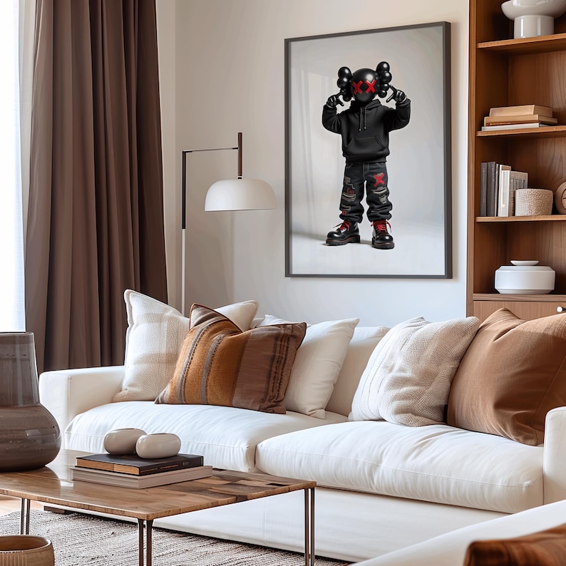 May include: A black and white illustration of a cartoon character wearing a black hoodie and jeans. The character has red X's for eyes and is standing with its arms raised. The illustration is framed and hanging on a white wall.