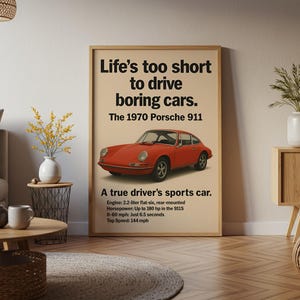 May include: Framed poster featuring a red 1970 Porsche 911 sports car. The poster has the text "Life's too short to drive boring cars." and car specifications. The poster is displayed in a living room setting.
