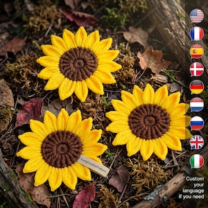 May include: Three handmade crochet sunflowers with yellow petals and brown centers rest on a bed of moss and leaves. The sunflowers are arranged in a natural setting, with a small tag that reads "Funny Crochet Pattern".