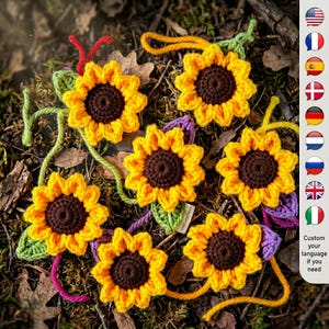 Puede incluir: Girasoles de ganchillo hechos a mano con pétalos amarillos y centros marrones, dispuestos sobre un lecho de hojas y ramitas. Cada girasol tiene un tallo y una hoja verdes, con detalles de hilo de colores. Los girasoles miden aproximadamente 7.6 cm de diámetro.