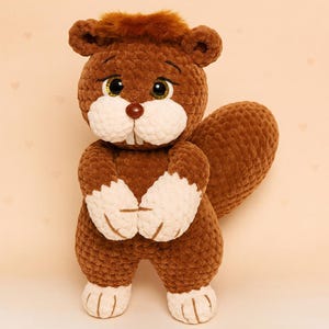 May include: A handmade brown and white plush squirrel toy with a fluffy tail. The squirrel has a brown nose, large black eyes, and white accents on its paws and face. The toy is standing upright and appears to be made of soft, textured material.