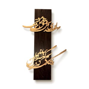 May include: A wooden wall art piece featuring two lines of elegant calligraphy in a light brown color, mounted on a dark brown rectangular wooden base. The calligraphy appears to be in a script style, adding a touch of artistic flair.