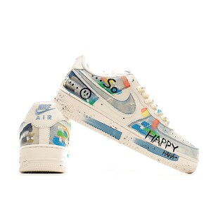 Puede incluir: Zapatillas Nike Air Force 1 blancas y azules con arte de graffiti personalizado. Las zapatillas presentan una carita sonriente, la palabra "So" y las palabras "HAPPY HAHA" en negro. Los zapatos tienen un patr&oacute;n similar al denim y acentos coloridos.