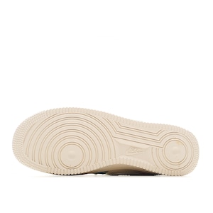 Puede incluir: Primer plano de la suela de una zapatilla beige. La suela presenta un patr&oacute;n texturizado con c&iacute;rculos conc&eacute;ntricos y ranuras lineales. El logotipo de Nike es visible cerca del tal&oacute;n. El calzado est&aacute; dise&ntilde;ado para uso deportivo.