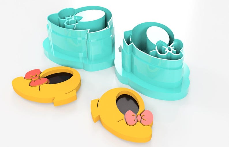 May include: A set of cookie cutters in the shape of a shoe with a bow. The cutters are yellow with a pink bow and black interior. Two teal-colored cutters are also present. These are likely for baking or crafting.