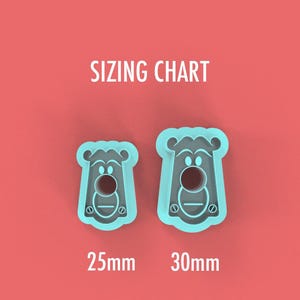 May include: Two teal-colored bear-shaped cookie cutters on a coral background. The cutters are in different sizes, with the text "SIZING CHART" above them. The sizes are labeled as 25mm and 30mm.