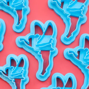 Könnte beinhalten: Ein Set mit sechs blauen Plastik-Ausstechern in Form von Feen. Die Ausstecher sind so konzipiert, dass sie Kekse in Form einer Fee ausstechen.