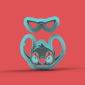 Może przedstawiać: Turkusowy zestaw foremek do ciastek z postacią Stitcha z Lilo & Stitch. Zestaw zawiera twarz i parę okularów, oba w kolorze turkusowym, na czerwonym tle. Foremka do ciastek jest przeznaczona do pieczenia.