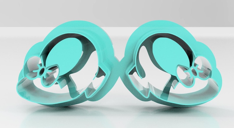 May include: Two turquoise cookie cutters in the shape of a hat with a bow. The cutters are made of plastic and have a smooth, glossy finish. The design is symmetrical, with each cutter mirroring the other.