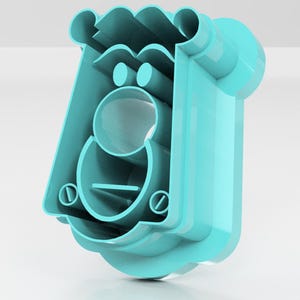 May include: A light blue plastic cookie cutter in the shape of a cartoon face. The cutter has a rectangular body with a rounded top and a circular opening for the mouth. Two small circles form the eyes, and a horizontal line represents the mouth.