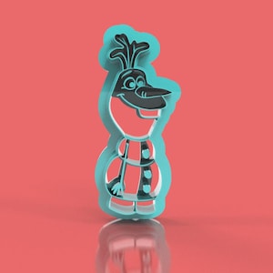 May include: A teal-colored Olaf-shaped cookie cutter with black and red accents. The cutter features a detailed outline of Olaf's face, body, and clothing. The background is a solid coral color, and the cutter is reflected on the surface below.