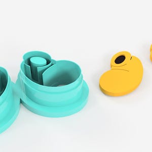 May include: A set of turquoise cookie cutters and two yellow cookie cutters shaped like cartoon character shoes. The cookie cutters are made of plastic and are on a white background.