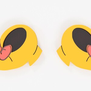 May include: Two yellow shoe-shaped decorations with black interiors and coral-colored bows. The shoes have a rounded shape with a small heel and are set against a white background. The bows have a dark pink outline.