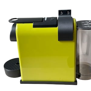Może przedstawiać: Limonkowo-zielony ekspres do kawy z czarnymi detalami, w tym uchwytem i tacką ociekową. Dołączony jest przezroczysty zbiornik na wodę. Nowoczesny design do kuchni.