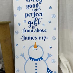 May include: A white wooden sign with blue text that reads "every good and perfect gift is from above -James 1:17-". The sign features a snowman graphic with a blue scarf and snowflakes.