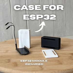Op de afbeelding: Een witte en zwarte ESP32-modulebehuizing met de tekst "CASE FOR ESP32" en "ESP32 MODULE INCLUDED". De behuizing bevat een witte afdekking, een zwarte basis en een zwarte printplaat met draden.