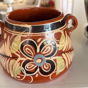 May include: A white ceramic mug with a black handle and the text "But First, Coffee" in a black, handwritten-style font. The mug is on a white surface.