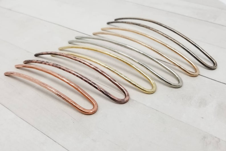 May include: A set of eight hair pins in various metallic finishes, including copper, brass, silver, and gold. The pins are all slightly curved and have a hammered texture.