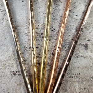 May include: Close-up of five metal rods in different finishes: antiqued bronze, bright bronze,  'Nugold' (red brass), bright copper, and antiqued copper.