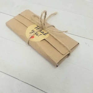 May include: A brown paper package tied with twine and a yellow circle sticker that says "Thank you!"