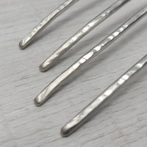 May include: Four silver metal hair combs with a hammered texture.