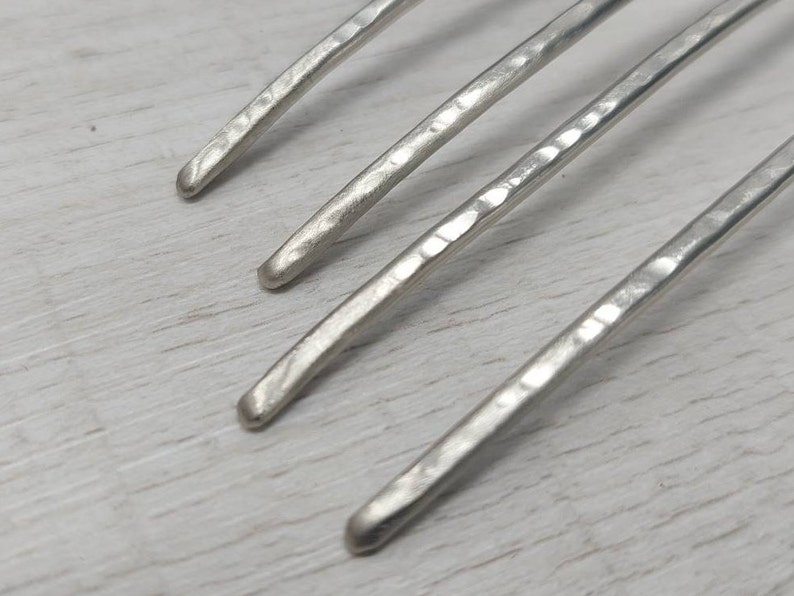 May include: Four silver metal hair combs with a hammered texture.