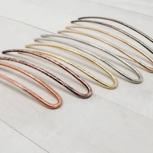 May include: A set of eight hair pins in various metallic finishes, including copper, brass, silver, and gold. The pins are all slightly curved and have a hammered texture.