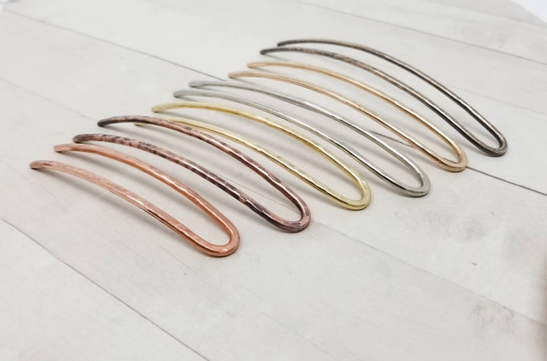May include: A set of eight hair pins in various metallic finishes, including copper, brass, silver, and gold. The pins are all slightly curved and have a hammered texture.