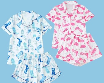 May include: Two sets of pajamas with short sleeves and shorts. One set is white with blue cowboy boot print and the other is white with pink cowboy boot print.