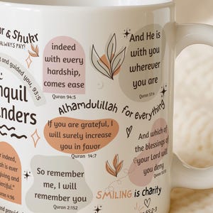 May include: White ceramic mug with inspirational quotes and floral accents. The mug features phrases like "Tranquil reminders" and "Alhamdulillah for everything" in a mix of fonts and colors. A perfect gift for anyone.