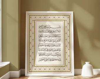 Op de afbeelding: Een ingelijste print met Arabische kalligrafie in zwarte letters. Het kunstwerk staat in een witte lijst met een decoratieve rand van gouden en rode geometrische patronen. De print wordt tentoongesteld op een houten vloer, met een witte vaas in de buurt.